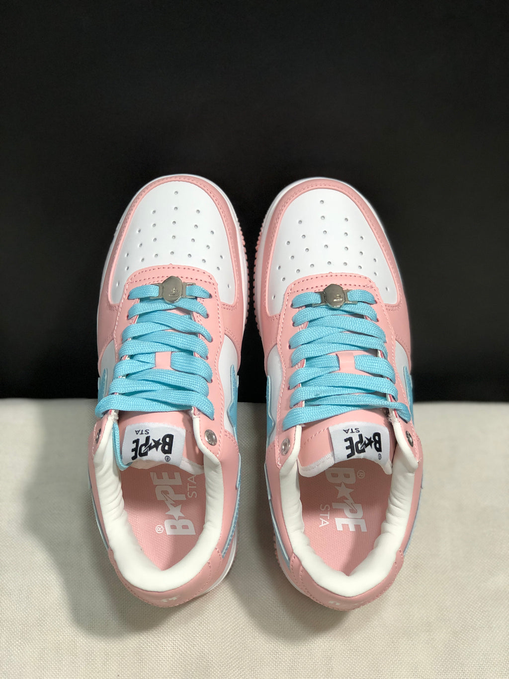 Top-down view showing the white perforated toe boxes, light-blue laces, and pink overlays.