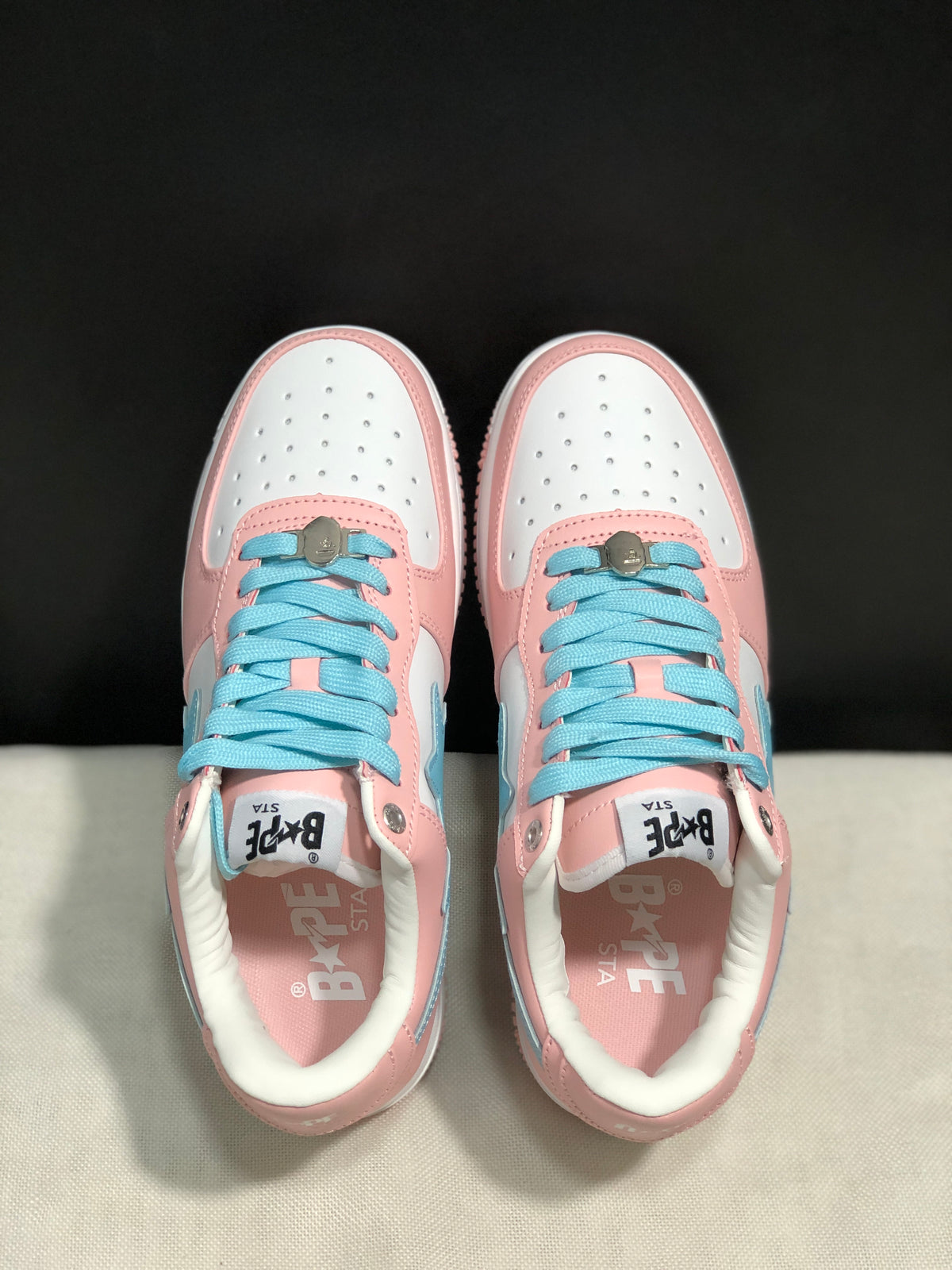 Top-down view showing the white perforated toe boxes, light-blue laces, and pink overlays.
