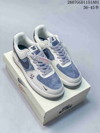 Pair of white and gray-blue low-top sneakers with dark Swooshes and patterned laces.