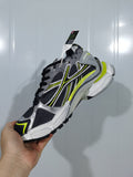 Angled view of grey, black, white and neon yellow Puma runner-style sneaker with layered side overlays and a chunky sole.