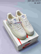 Cream Nike Air Force 1 '07 x Stussy sneakers displayed on a Nike shoebox.