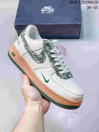 White low-top sneaker with green patterned accents and a peach-colored midsole