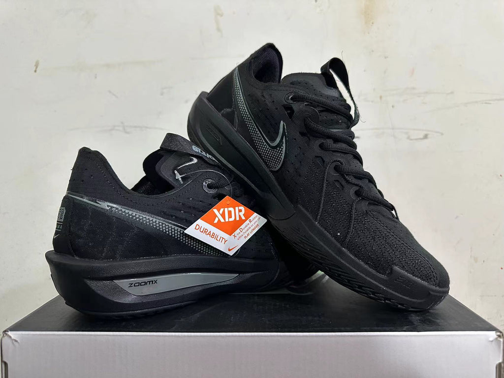 Pair of all-black Nike sneakers showing side profile, dotted Swoosh, and textured outsole
