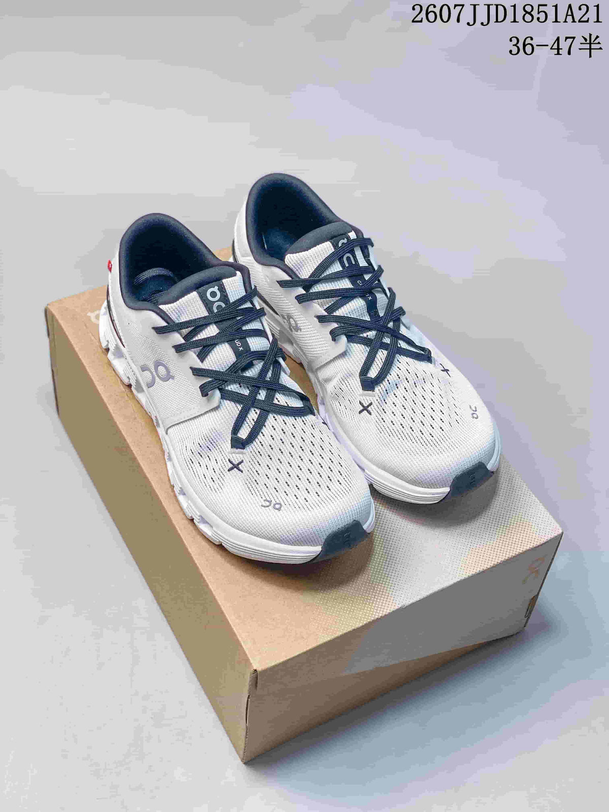 Pair of white and navy On Cloud X 4 sneakers displayed on a shoebox from a front three-quarter angle.