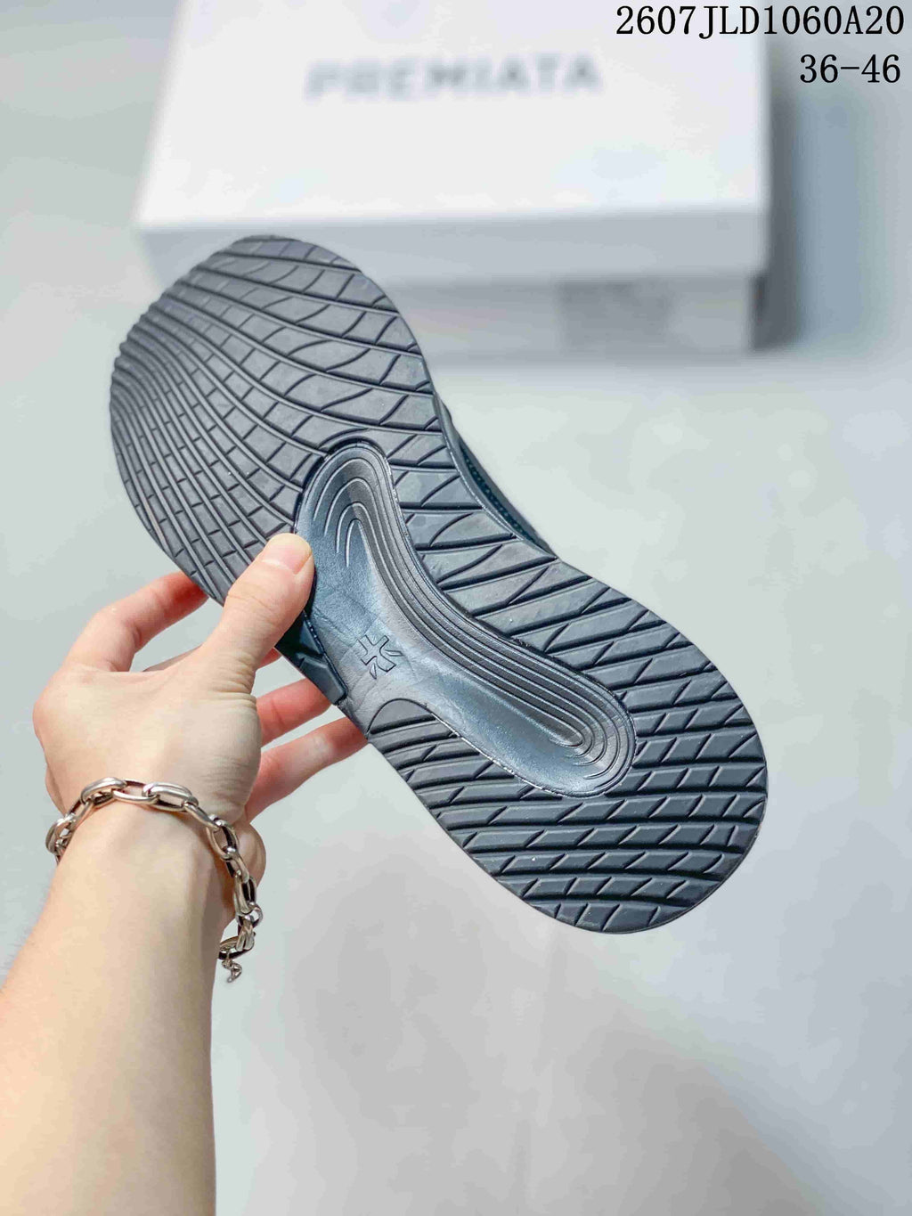 Underside view of a black trainer showing the patterned rubber outsole and tread design.