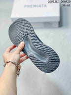 Underside view of a black trainer showing the patterned rubber outsole and tread design.