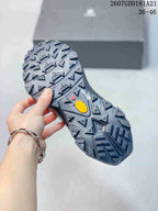 Close view of the lugged outsole with angular tread blocks and a yellow insert.