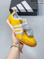 Side view of a yellow JOG 2.0 sneaker with white stripes