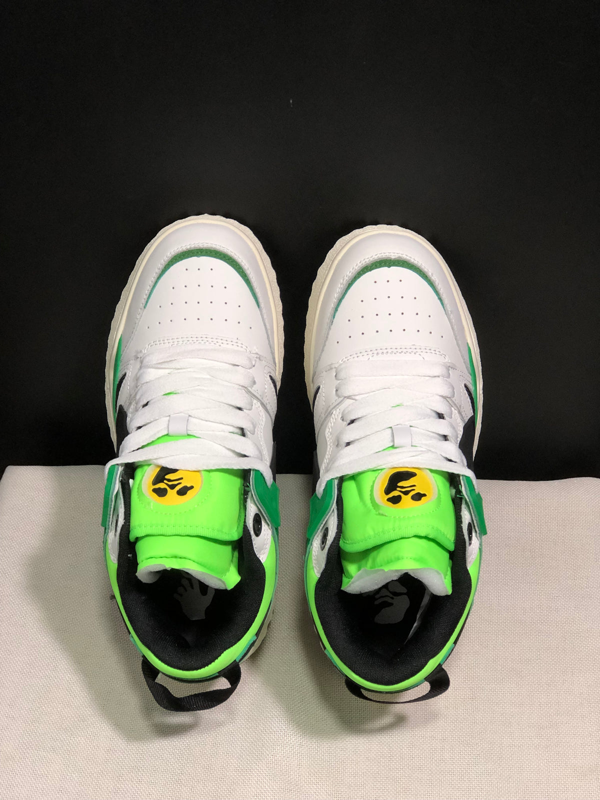 Top view showing white perforated toe boxes, white laces, neon green tongues, and black inner lining.