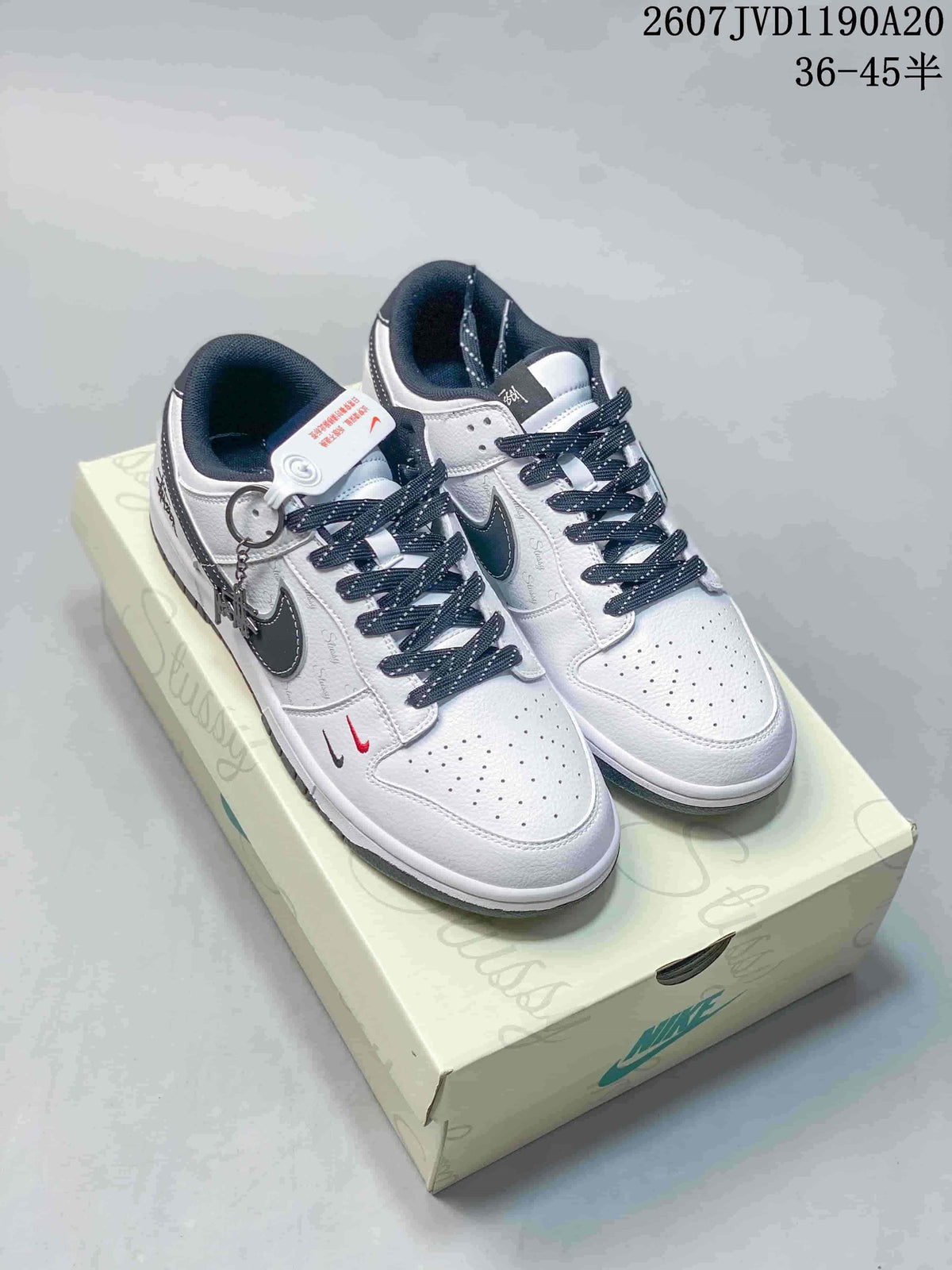 Pair of off-white and black Nike SB Dunk Low sneakers with dark laces and contrasting side branding.