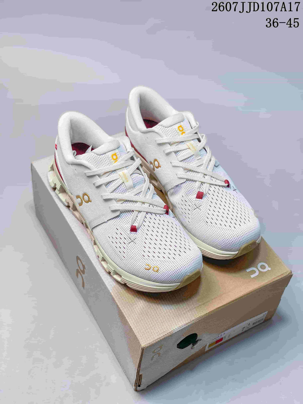Pair of white On Running Cloud X 4 AD sneakers with gold branding, red accents, and a shoebox.