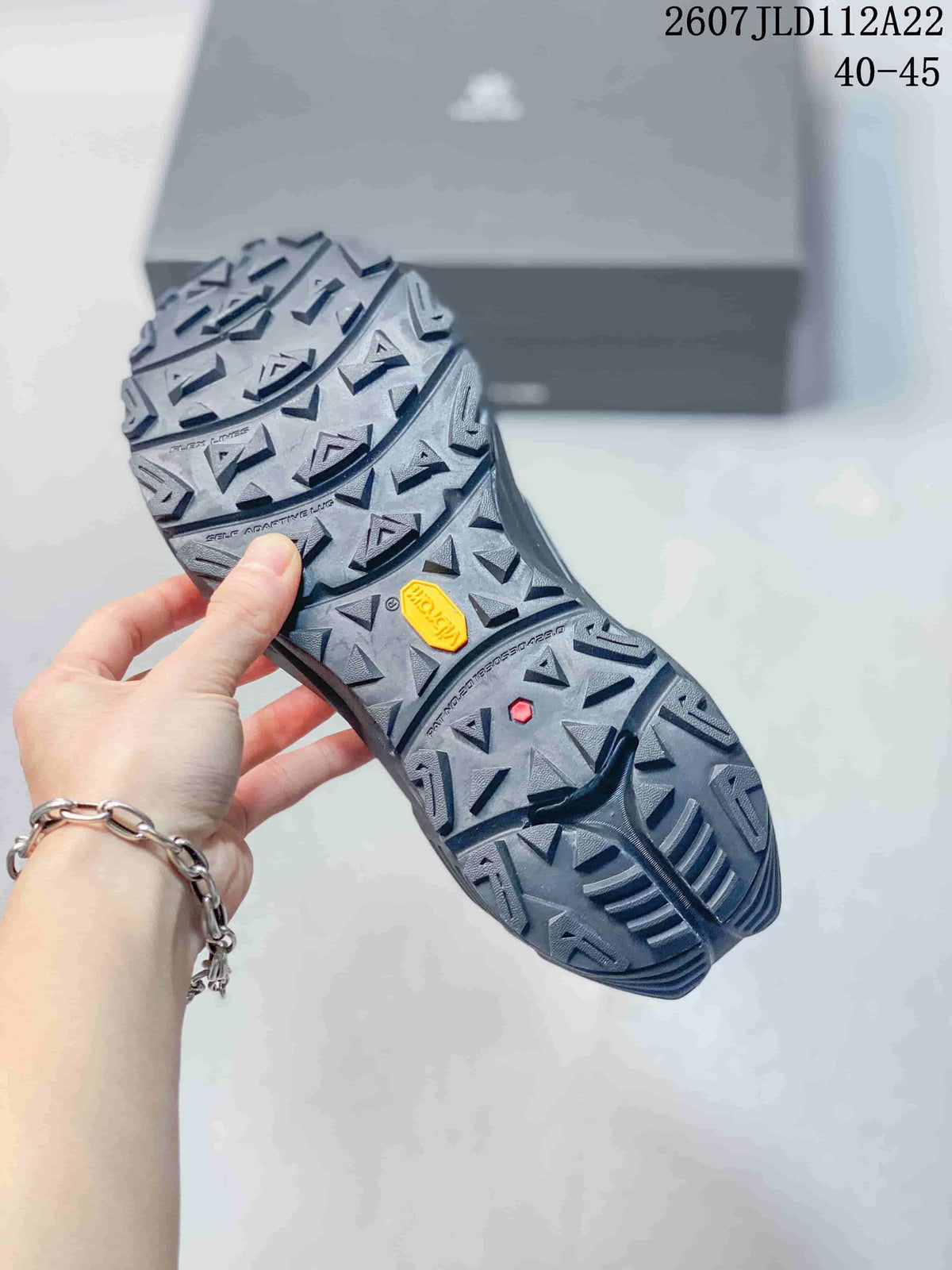 Close view of the heavily lugged outsole, showing angular tread and a visible Vibram marking; code 2607JLD112A22 and size range 40–45 are overlaid.