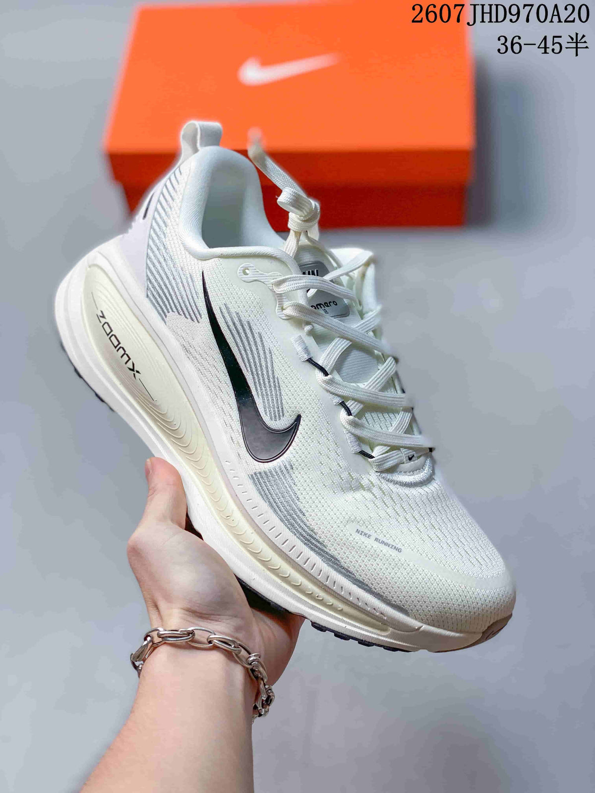 White Nike Structure Plus running sneaker with a black Swoosh and pale midsole, displayed beside an orange shoebox.
