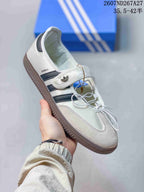 Angled side view of the white adidas Samba Jane sneaker with dark stripes, strap detail and gum-colored outsole.