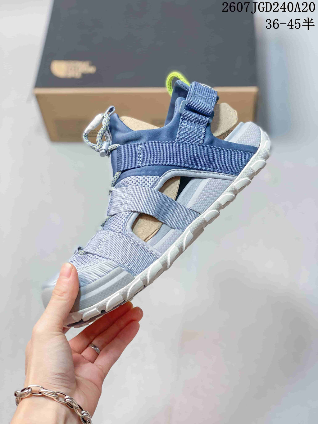 Side view of the blue open-toe sandal showing its layered webbing straps, mesh panels and white outsole.