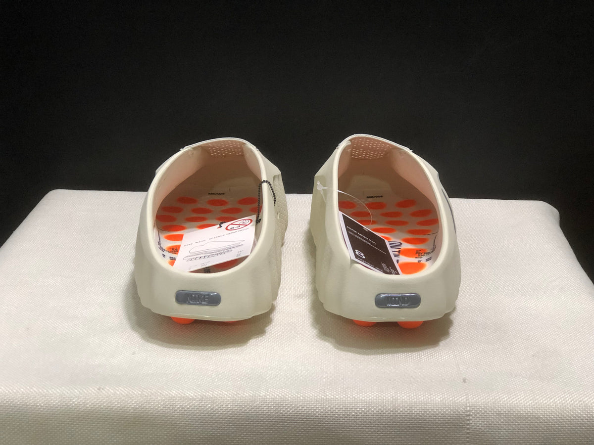 Rear view of the pair showing the open-back mule shape, textured insoles, and orange outsole pods.