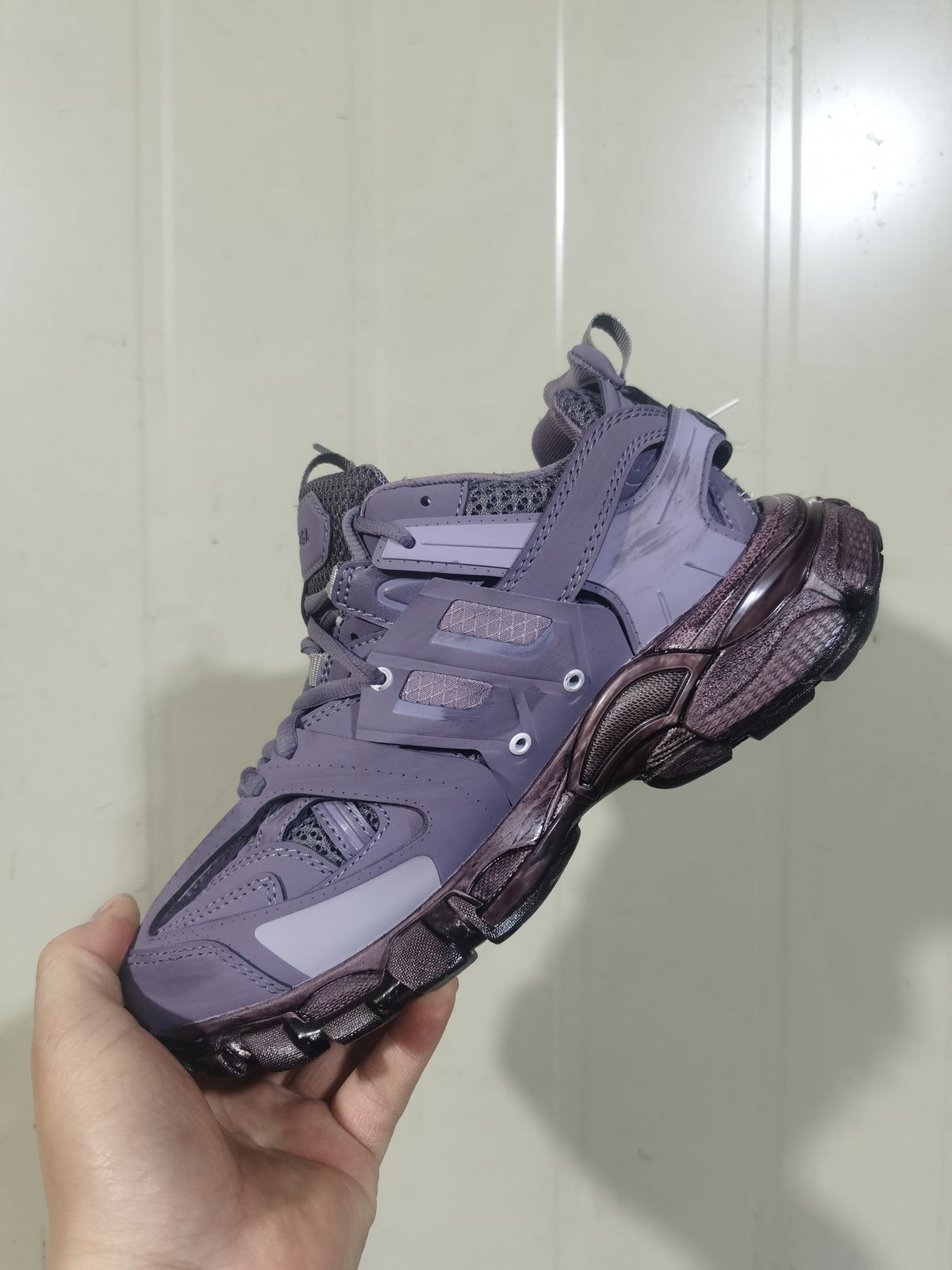 Rear and lateral view of the lavender Balenciaga Track sneaker, showing layered heel panels, mesh details, pull tabs, and the dark sculpted outsole.