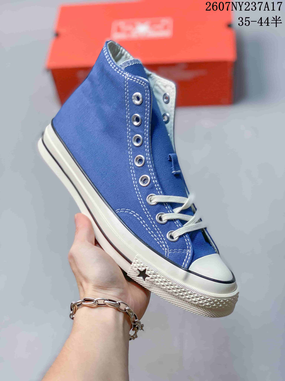 Angled side view of the blue Converse high-top sneaker with white laces, rubber toe cap, and textured sole.