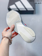 Underside view showing the light-colored outsole and recessed traction grooves of the gray and red running shoe.