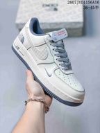 Close-up side view of a white sneaker with a grey patterned Swoosh, perforated toe box, lace-up front, and Air sole branding.
