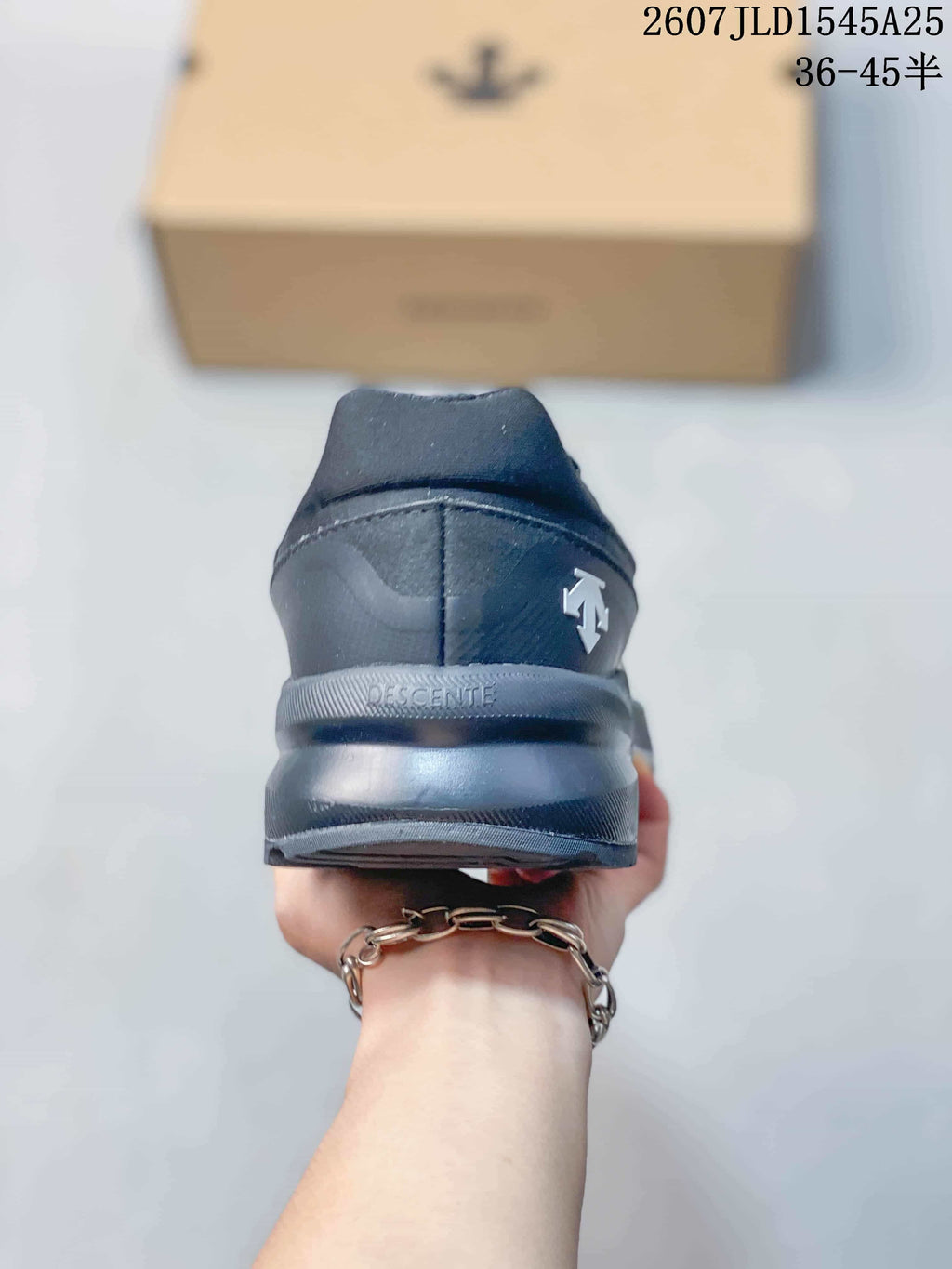 Rear view of the black sneaker showing the heel construction, DESCENTE branding, and heel logo detail.