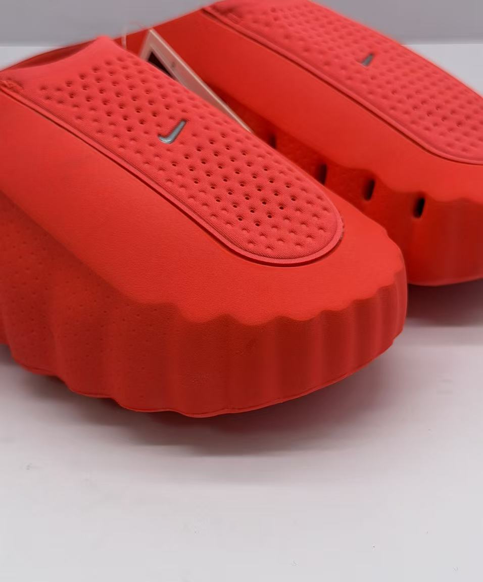 Close-up of the perforated footbed and small Swoosh detail on an orange-red slide.