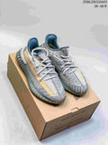 Pair of grey and tan Adidas Yeezy Boost 350-style sneakers displayed on a shoebox.