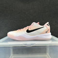 Side view of a white and pink low-top Nike basketball sneaker with a black Swoosh.