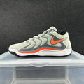 Light gray Nike basketball-style sneaker with dark gray overlays and red-orange accents