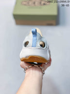 Rear view showing the heel pull tab, open heel area, white upper, and tan outsole.