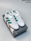 Pair of white adidas Adipista trainers with green stripes and gum outsoles displayed on a shoebox