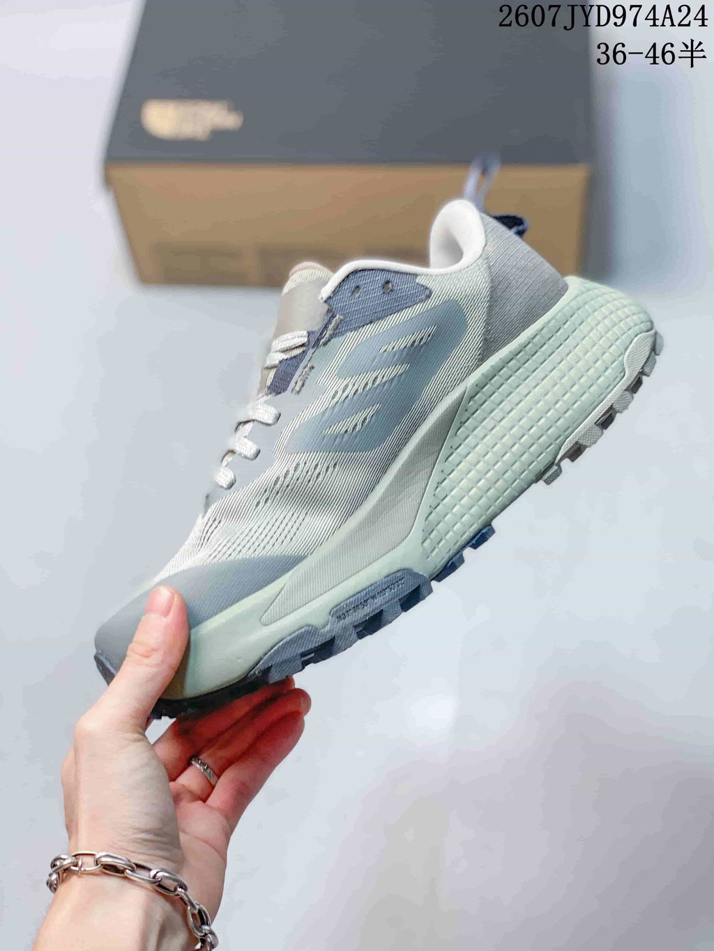 Side profile of the gray low-top sneaker showing its layered upper, pale green midsole and dark outsole.