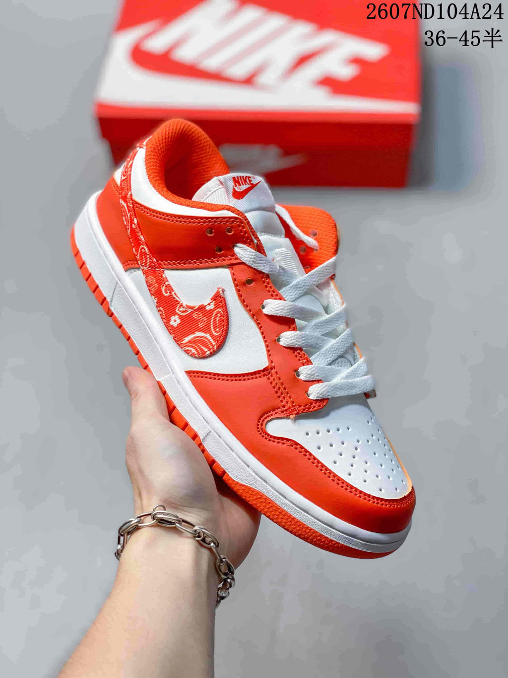 Close-up side view of a white and orange low-top sneaker with a patterned Nike Swoosh.
