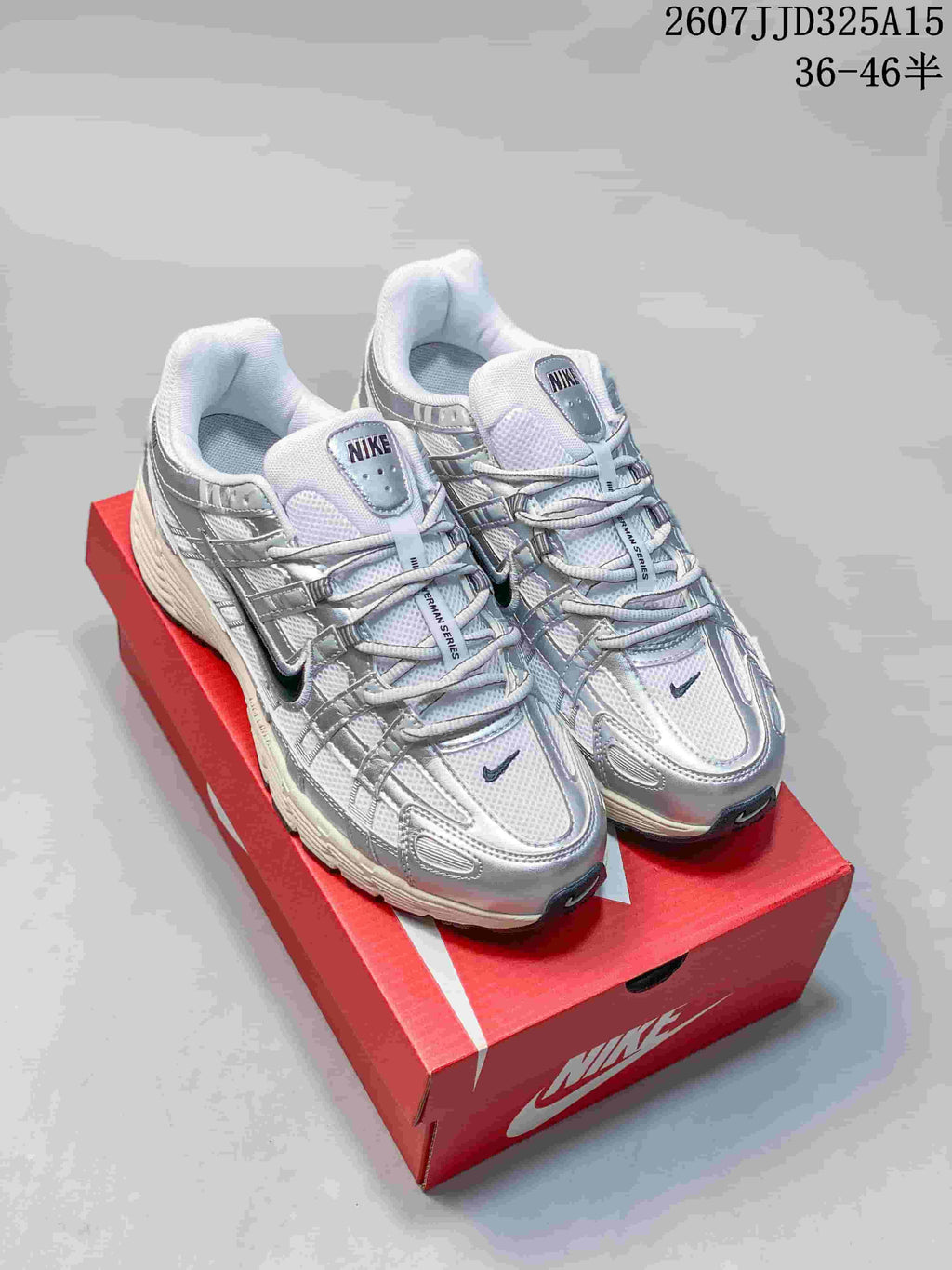 Pair of silver and white Nike P-6000 Initiator sneakers displayed on a red shoebox; overlay text shows 2607JJD325A15 and sizes 36–46.5.