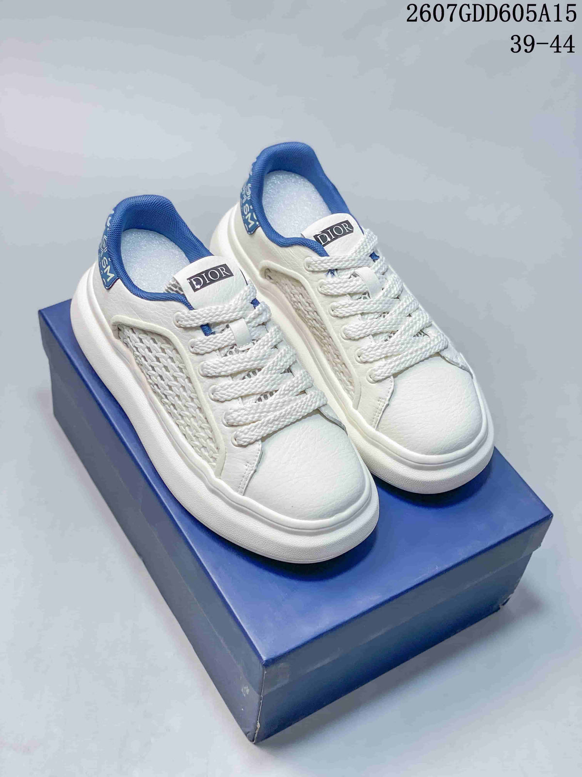 Pair of white Dior low-top sneakers with blue collar accents, white laces, and woven side panels displayed on a blue shoe box; overlay shows style code 2607GDD605A15 and size range 39–44.