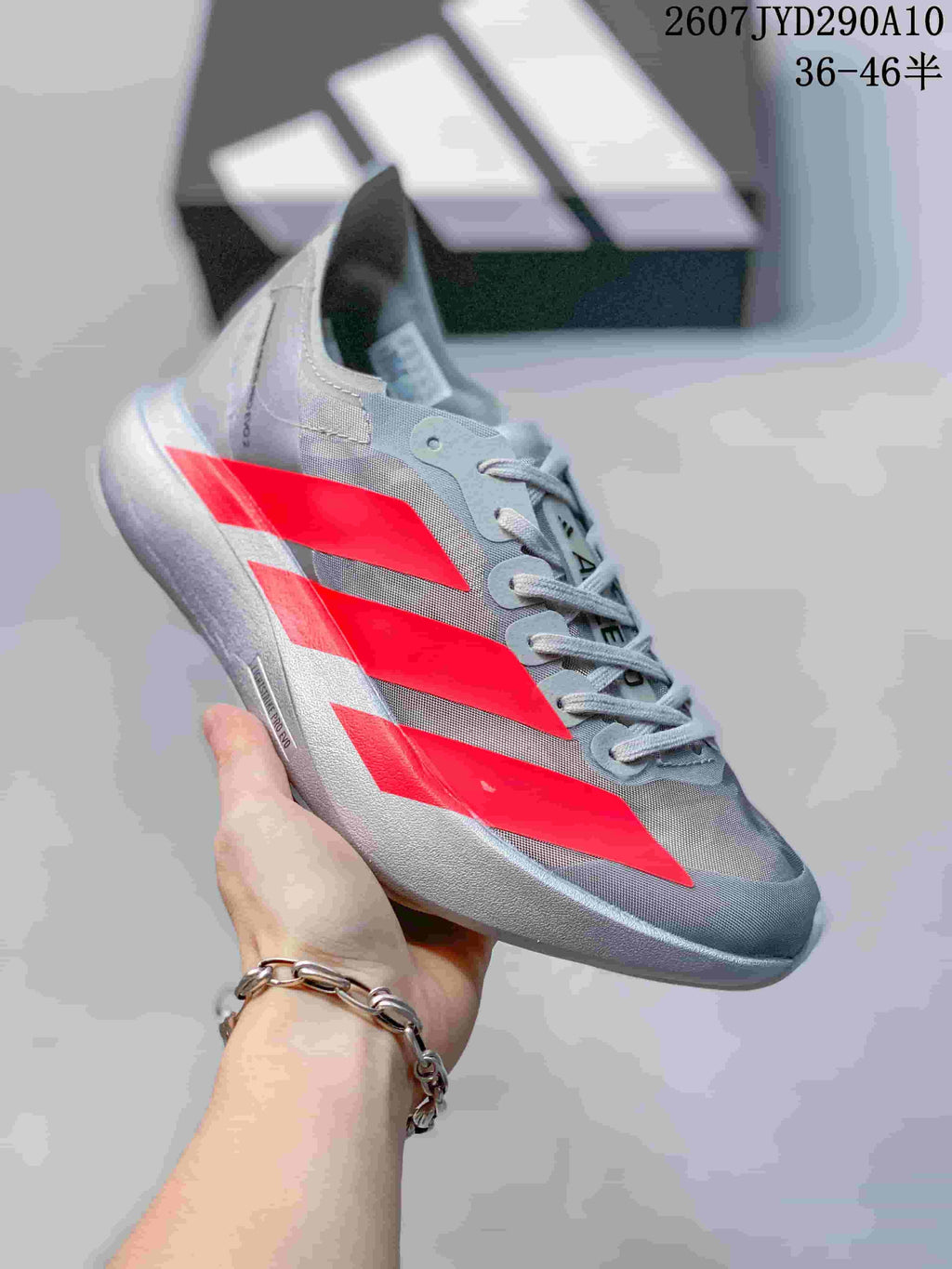 Side view of the silver-gray Adidas Adizero Adios Pro Evo 2 shoe with bright red panels and a contrasting sole.