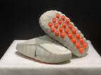 Angled outsole view showing the sculpted sole and multiple orange circular pods.