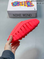 Side view of a red Nike Mind slide showing ventilation openings and the sculpted outsole.