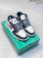 Pair of black, white and grey low-top sneakers displayed on a green presentation box.