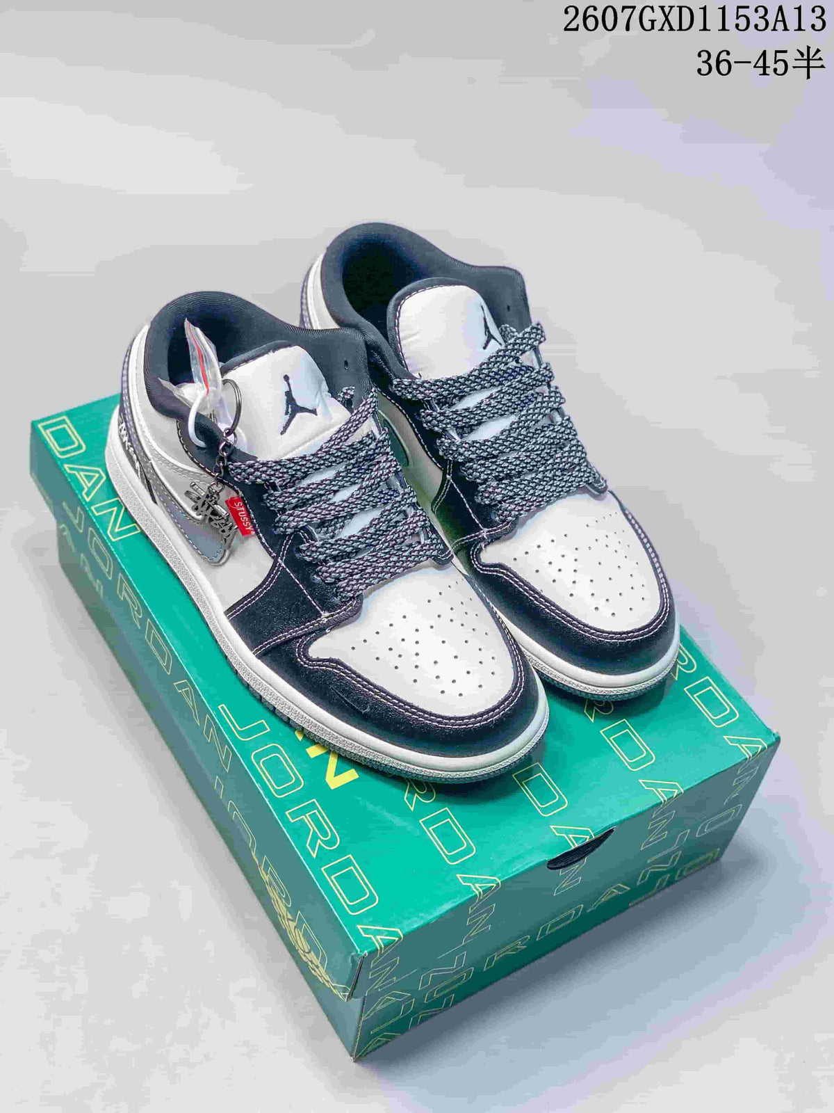 Pair of black, white and grey low-top sneakers displayed on a green presentation box.