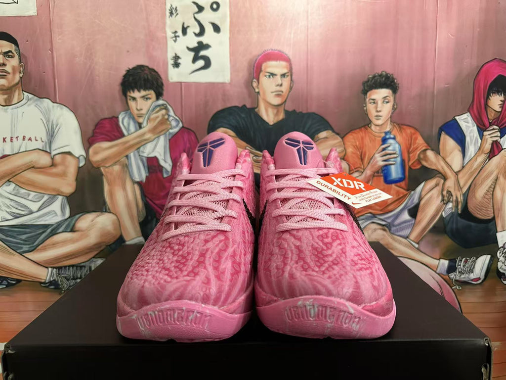 Front view of pink Nike basketball sneakers with matching laces, textured uppers, black tongue logos, and a visible durability tag.