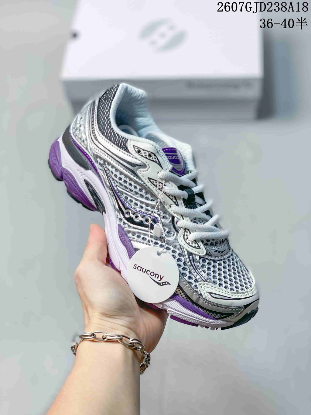 Angled view of a Saucony Progrid Omni 9 sneaker showing the mesh-style upper, layered overlays, purple accents and branded hangtag.