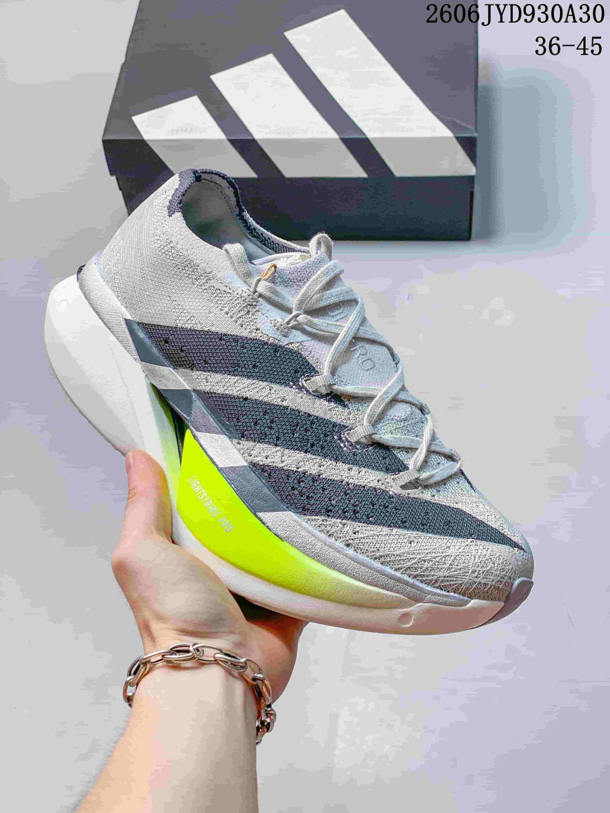 Light gray adidas Adizero Prime X3 shoe with dark stripes and a neon yellow sole accent.
