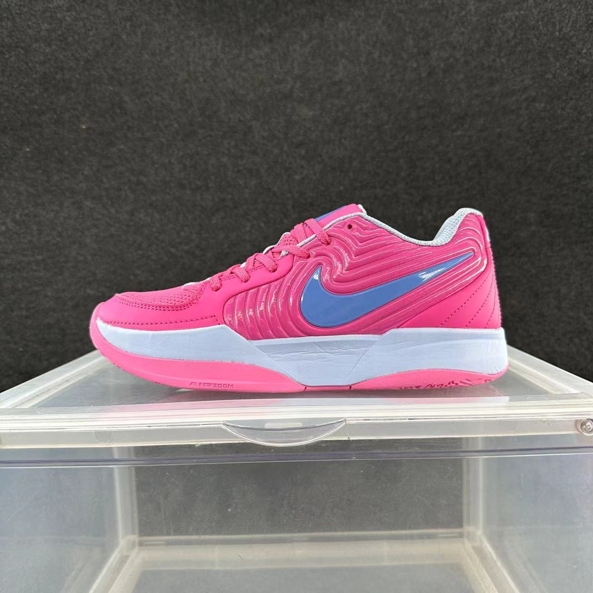 Side view of pink Nike low-top court sneakers with a blue Swoosh, white midsole, and pink outsole.