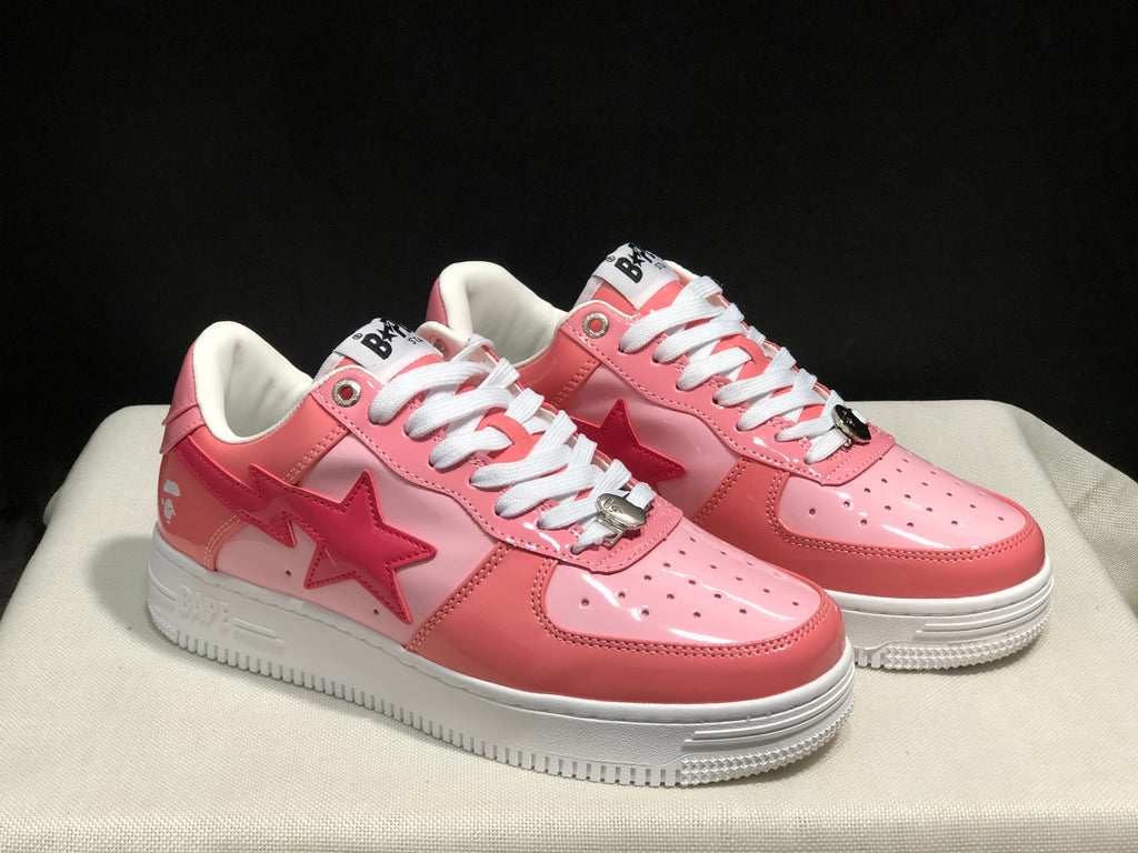 Three-quarter front view of the pair showing the pink upper, star side graphics, white laces, and white midsoles.