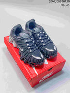 Pair of dark Nike Shox TL sneakers with silver accents on a red shoebox