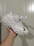 White and black chunky sneaker shown from the outer side, highlighting its layered upper and raised lugged outsole.
