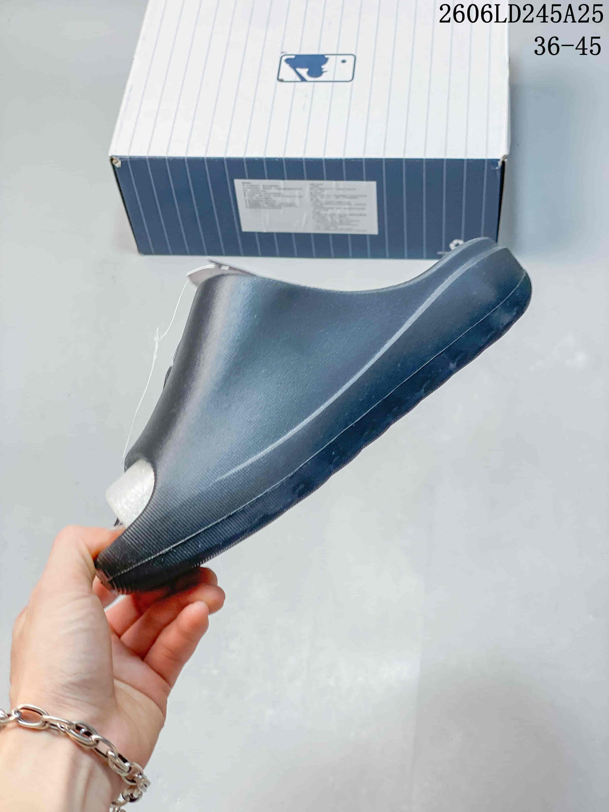 Side profile of a black open-toe slide sandal, showing the molded sole and raised upper shape.