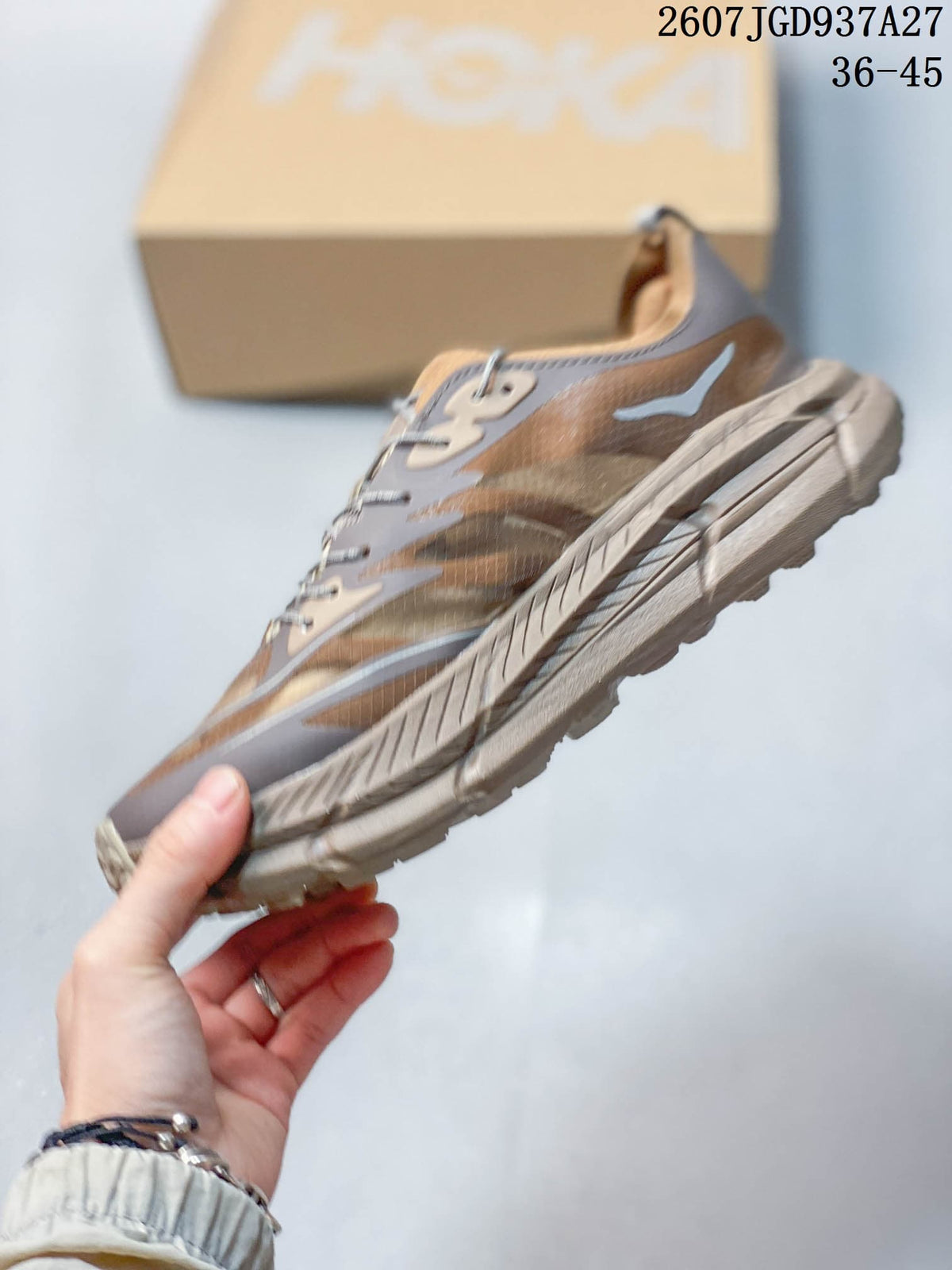 Side profile of a brown and taupe low-top sneaker showing the layered upper and sculpted sole.
