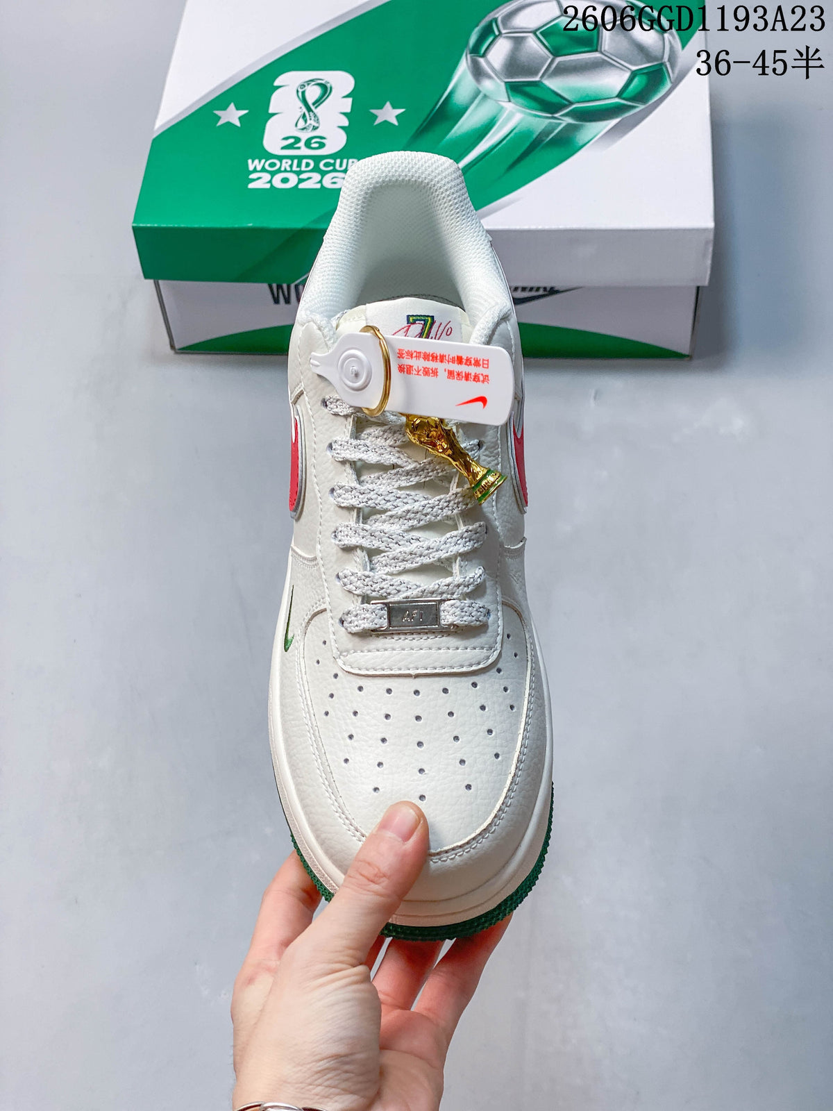 Top view of the white sneaker showing perforated toe, laces, and a trophy-shaped charm.